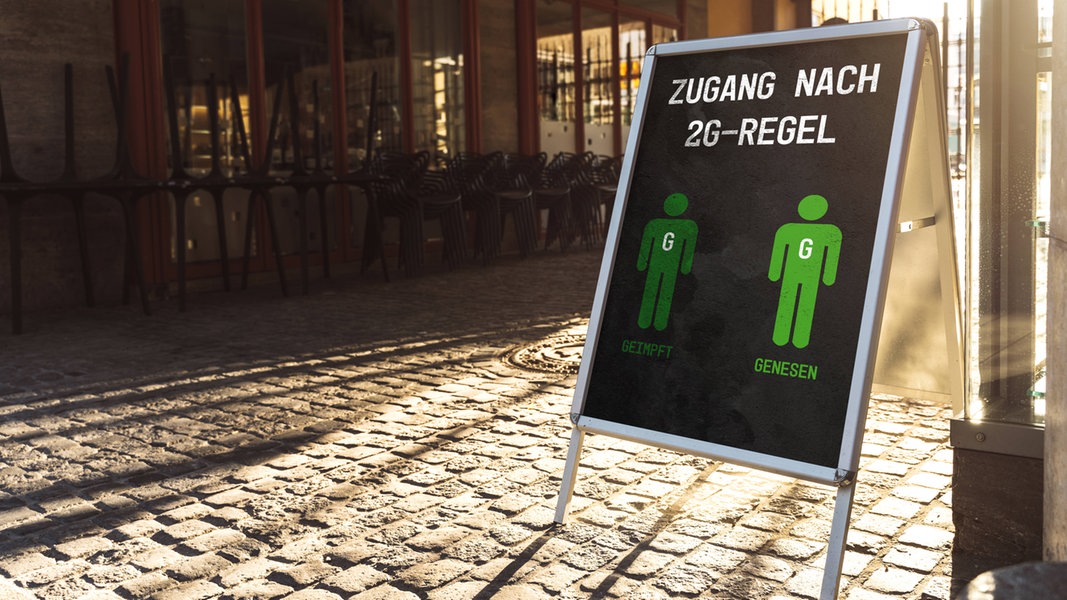 Vor einer Gaststätte steht ein Schild, das auf die 2G-Regel hinweist. 