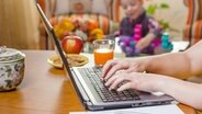 Eine Frau arbeitet zu Hause bei ihrem Kind an einem Laptop. © panthermedia Foto: doble dphoto