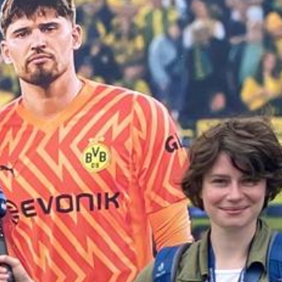 London Korrespondentin Franziska Hoppen vor einem Plakat mit Borussia Dortmund-Fußballspielern © NDR Foto: Franziska Hoppen