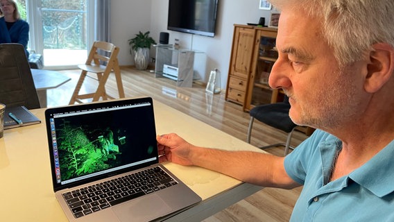 Henry Horn blickt auf einen Computerbildschirm, auf dem Aufnahmen eines Nachtmarsches zu sehen sind, bei dem sein Sohn ums Leben kam. © NDR Foto: Stefan Schölermann