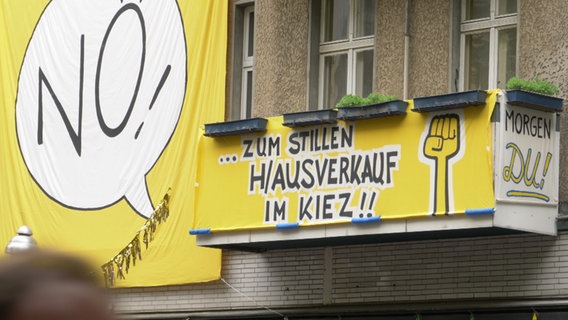 An an einem Haus hängt ein Protestplakat gegen den Mietenwahnsinn. Neben dem Schriftzug "No zum stillen Hausverkauf im Kiez!" ist eine gereckte Faust zu sehen. © NDR 