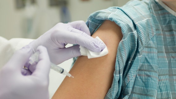 Il medico vaccina la parte superiore del braccio della persona.  © Immagine della scatola dei colori: -