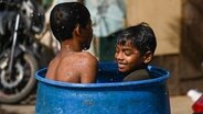 Zwei kleine Jungen in Indien erfrischen sich in einer Wassertonne © picture alliance Foto: Kabir Jhangiani