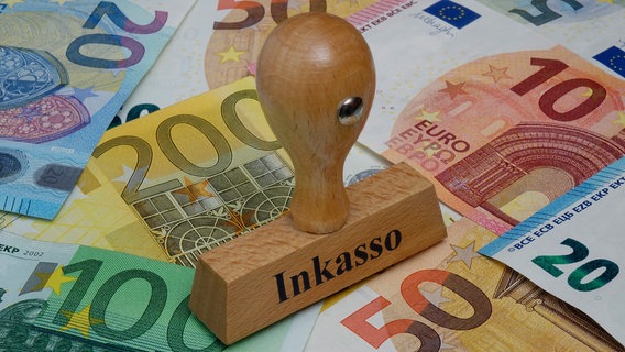 Ein Stempel mit der Aufschrift "Inkasso" steht auf verschiedenen Geldscheinen. © picture alliance/dpa-Zentralbild Foto: Sascha Steinach