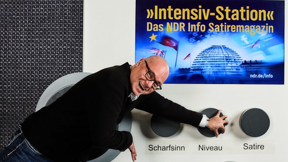 Moderator Markus Schubert steht vor einem riesigen Radio und dreht an einem Knopf, der mit "Niveau" beschriftet ist. © NDR Foto: Hendrik Lüders