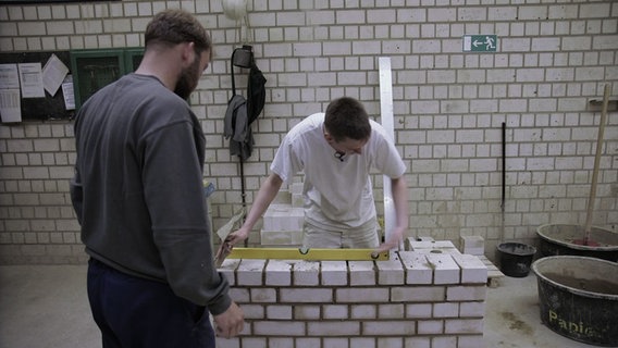 Zwei Häftlinge bauen eine Mauer. © NDR 