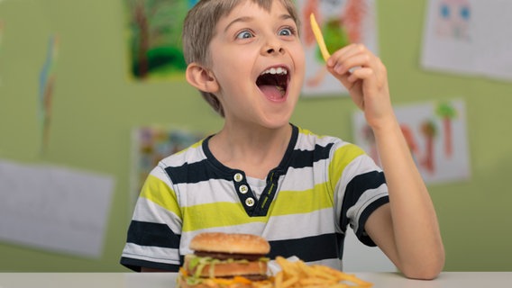 Junge hält freudig einen Pomme frite vor seine Augen. © fotolia Foto: Photographee_eu