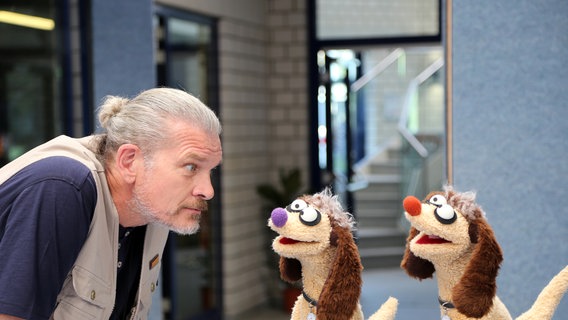 Der Hundetrainer (Götz Otto) starrt Jan und Henry an, die als Hunde verkleidet sind. © bigSmile/ NDR 