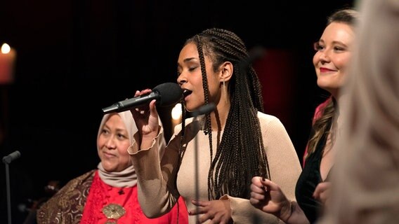 Eine junge Frau singt in ein Mikrofon. © Kirche im NDR Foto: Eva Häberle