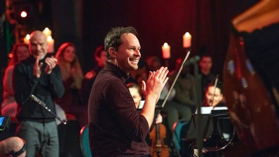 Chorleiter Michael Zlanabitnig lächelt und klatscht in die Hände. © Kirche im NDR Foto: Eva Häberle