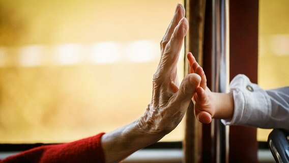 Eine alte Frauenhand und eine Kinderhand berühren sich. © photocase Foto: provid