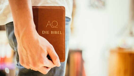 Ein junger Mann hält eine Bibel in einer Hand. © Colourbox Foto: Patrick Daxenbichler