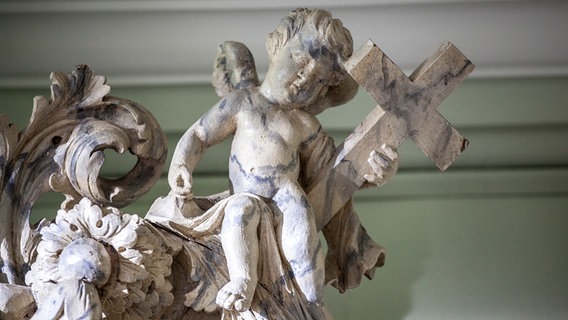 Ein Engel hält sich an einem Kreuz fest. © Kirche im NDR Foto: Christine Raczka