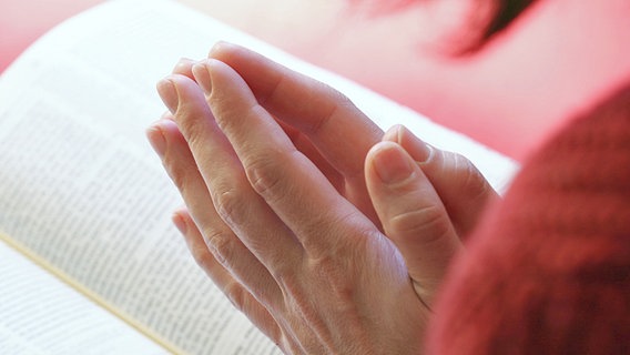 Frau betet über einer Bibel © Fotolia 