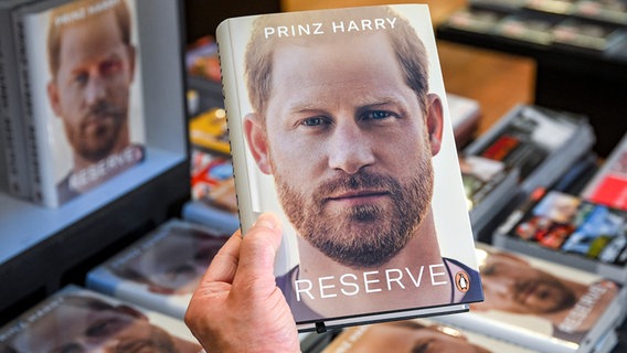 Jemand hält Prinz Harrys Autobiografie "Reserve" in der Hand. © picture alliance/dpa Foto: Jens Kalaene