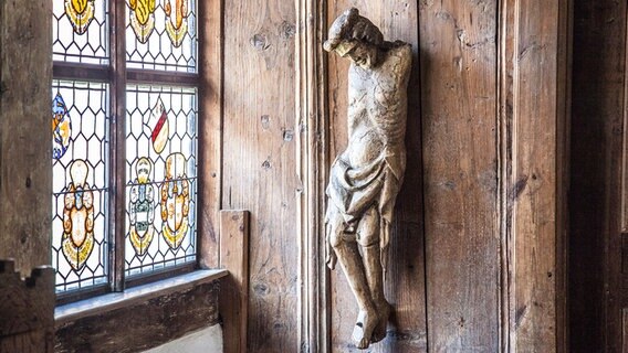 Eine Jesusfigur ohne Arme hängt an einer Holzwand. © Kirche im NDR Foto: Christine Raczka