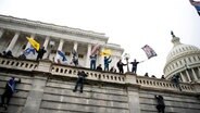 Anhänger von Präsident Donald Trump klettern in Washington auf die Westwand des US-Kapitols. © Jose Luis Magana/AP/dpa Foto: Jose Luis Magana