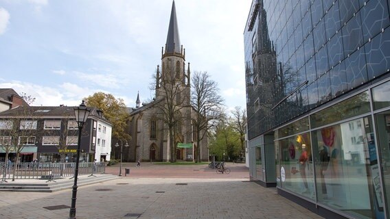 Die Martin-Luther-Kirche spiegelt sich in der Fassade des Einkaufsgeschäftes Karstadt in Gütersloh. © dpa Foto: Friso Gentsch