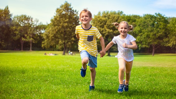 Zwei Kinder rennen lachend über eine Wiese. © colourbox Foto: spass