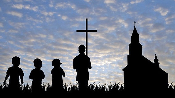 Kinder tragen im Sonnenuntergang ein Kreuz zur Kirche. © Fotolia Foto: Alex White