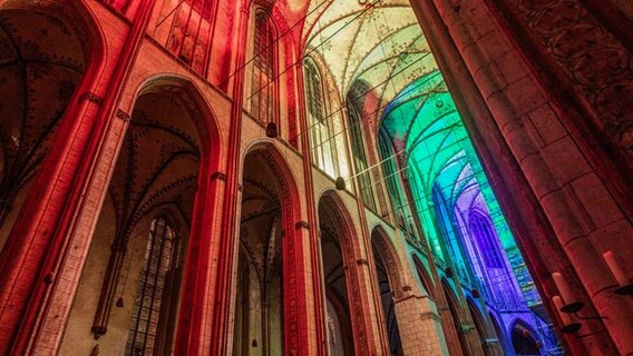 Das Innere der Marienkirche während des CSD in Regenbogenfarben beleuchtet. © Kirche im NDR Foto: Kevin Hackert
