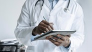 Ein Arzt im Kittel mit einem Tablett. (Symbolbild) © picture alliance / Westend61 Foto: Ok Shu