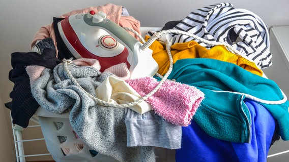 Ein Bügeleisen liegt in einem vollem Wäschekorb. © Colourbox Foto: -