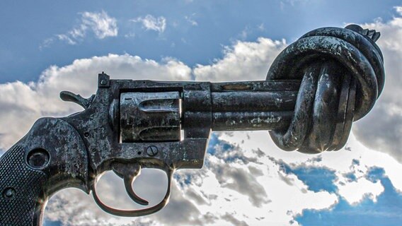 Eine übergroße Pistole mit Knoten im Lauf vor blauem Himmel. © picture alliance / Daniel Kalker Foto: Daniel Kalker