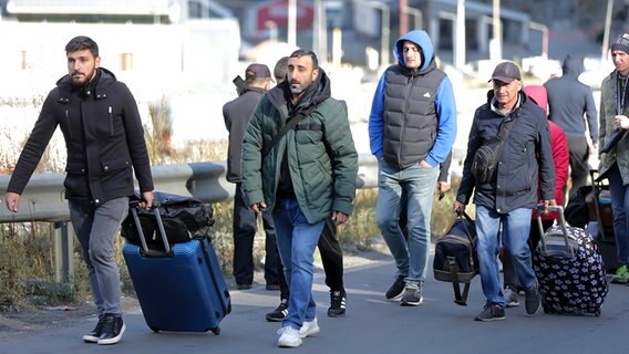 Eine Gruppe von Russen geht nach dem Passieren der russisch-georgischen Grenze in Werchni Lars in Georgien über eine Straße. © picture alliance/dpa/AP Foto: Zurab Tsertsvadze