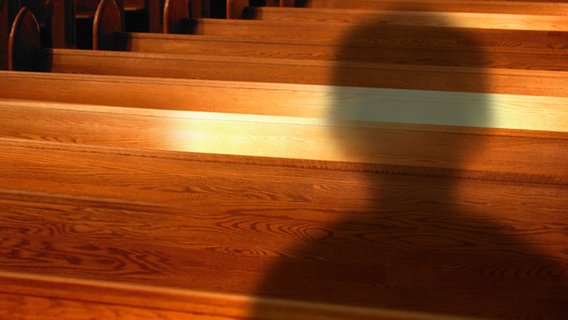 Montage: Schatten eines Jungen vor Kirchenbänken. © picture-alliance 
