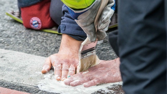 Umweltaktivisten der "Letzten Generation" haben sich auf der Straße festgeklebt. Detailaufnahme der Hände © picture alliance / ZUMAPRESS.com | Sachelle Babbar Foto: Sachelle Babbar