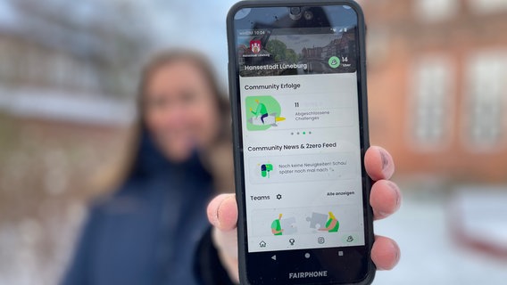 Eine Frau zeigt auf einem Smartphone die App "2zero" für den Klimathon. © Hansestadt Lüneburg 