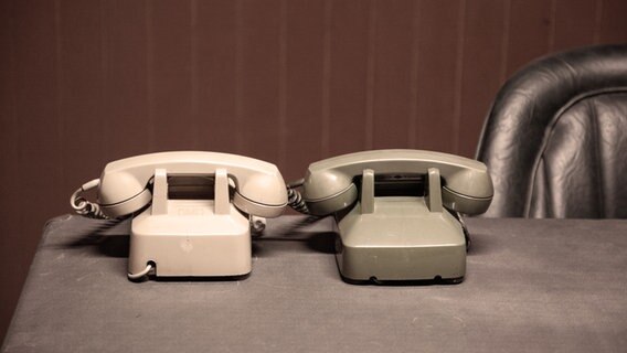 Zwei Wählscheibentelefone stehen auf einem Tisch mit Lederstuhl. © photocase / Zauberbart Foto: Zauberbart