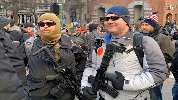 Zwei vermummte Männer bei einer Demonstration in Michigan tragen Maschinengewehre. © ARD Foto: Torben Ostermann
