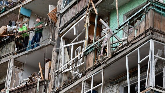 Menschen stehen im ukrainischen Kramatorsk auf dem Balkon eines beschädigten Wohnblocks. © ZUMA Press Wire/dpa Foto: Andriy Andriyenko/SOPA Images