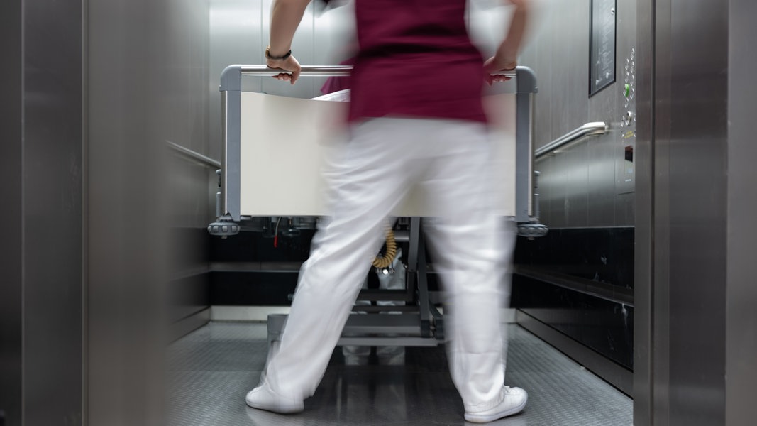 Eine Pflegerin schiebt ein Krankenbett in einen Fahrstuhl