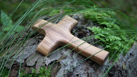 Holzkreuz unter Gräsern auf einem Baumstamm. © fotolia.com Foto: Jeanette Dietl