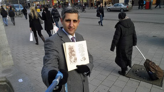 Michel Abdollahi mit Selfie-Stange und Buch. © NDR 