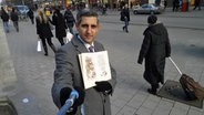 Michel Abdollahi mit Selfie-Stange und Buch. © NDR 