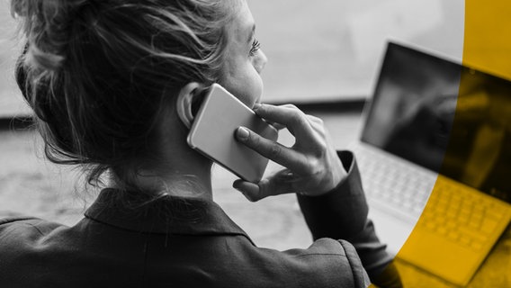 Themenbild des ARD Radiofeatures "Abgehört": Eine blonde Frau hat ein Telefon am Ohr. Vor ihr steht ein Laptop. Sie trägt eine lockere Hochsteckfrisur und blickt in die Ferne. © picture alliance / Westend61 