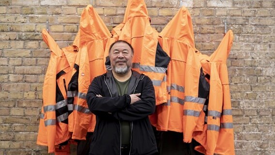 Ai Weiwei steht vor seinem Kunstwerk "Safety Jackets Zipped the Other Way" © picture alliance/Christoph Soeder/dpa Foto: Christoph Soeder