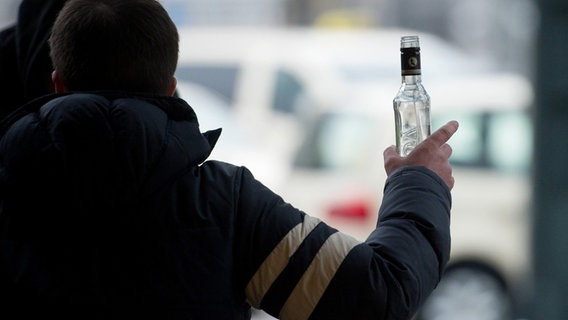 Ein stark alkoholisierter Mann gestikuliert am Hauptbahnhof mit einer Wodkaflasche in der Hand. © picture alliance/dpa Foto: Daniel Reinhardt