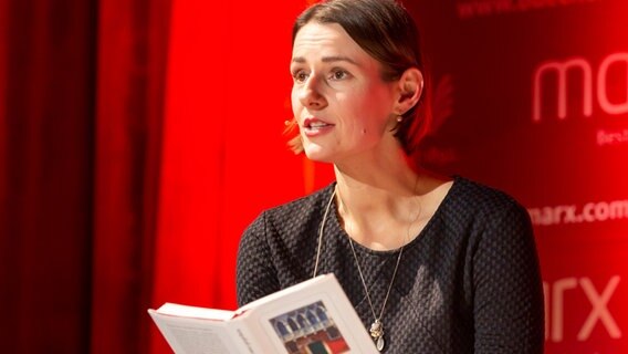 Annett Renneberg bei einer Lesung mit einem Buch in der Hand © picture alliance / Geisler-Fotopress | Tommy Giesel/Geisler-Fotopress 
