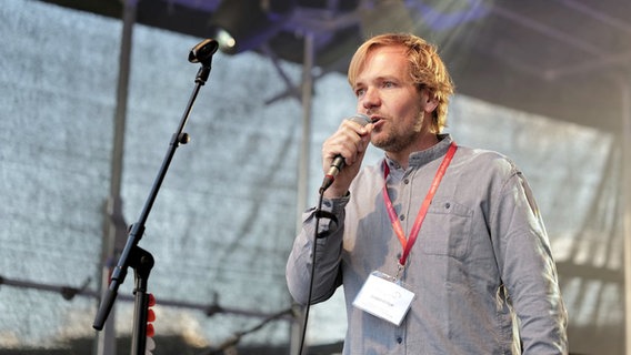 Gunnar Astrup (ein blonder Mann) singt in ein Mikrofon. © Kai Steffens 