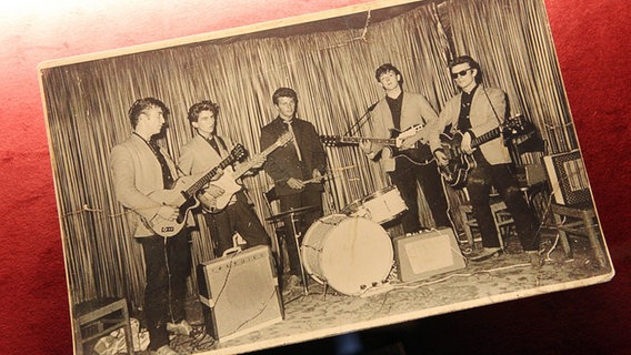 Ein Foto von den Beatles bei einem ihrer ersten Auftritte im Nachtclub "Indra" liegt auf einem roten Untergrund. © picture alliance / dpa Foto: Malte Christians