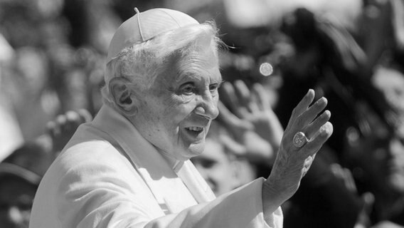 Papst Benedikt XVI. hebt die Hand zum Gruß © picture alliance Foto: Michael Kappeler