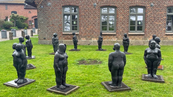Zwölf Frauen-Figuren aus Bronze stehen im Kreis in einem Vorgarten. © NDR Foto: Frank Hajasch