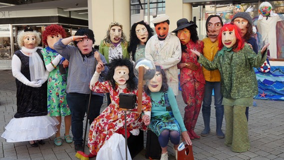 Maskierte Darstellende eines Straßentheater-Stücks posieren für eine Gruppenbild. © NDR Foto: Helgard Füchsel
