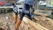 Zwei Frauen arbeiten mit Äxten an einem Baumstamm. © NDR Foto: Frank Hajasch