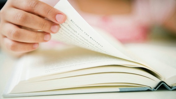 Eine Hand blättert eine Buchseite um. © picture alliance / Bildagentur-online 